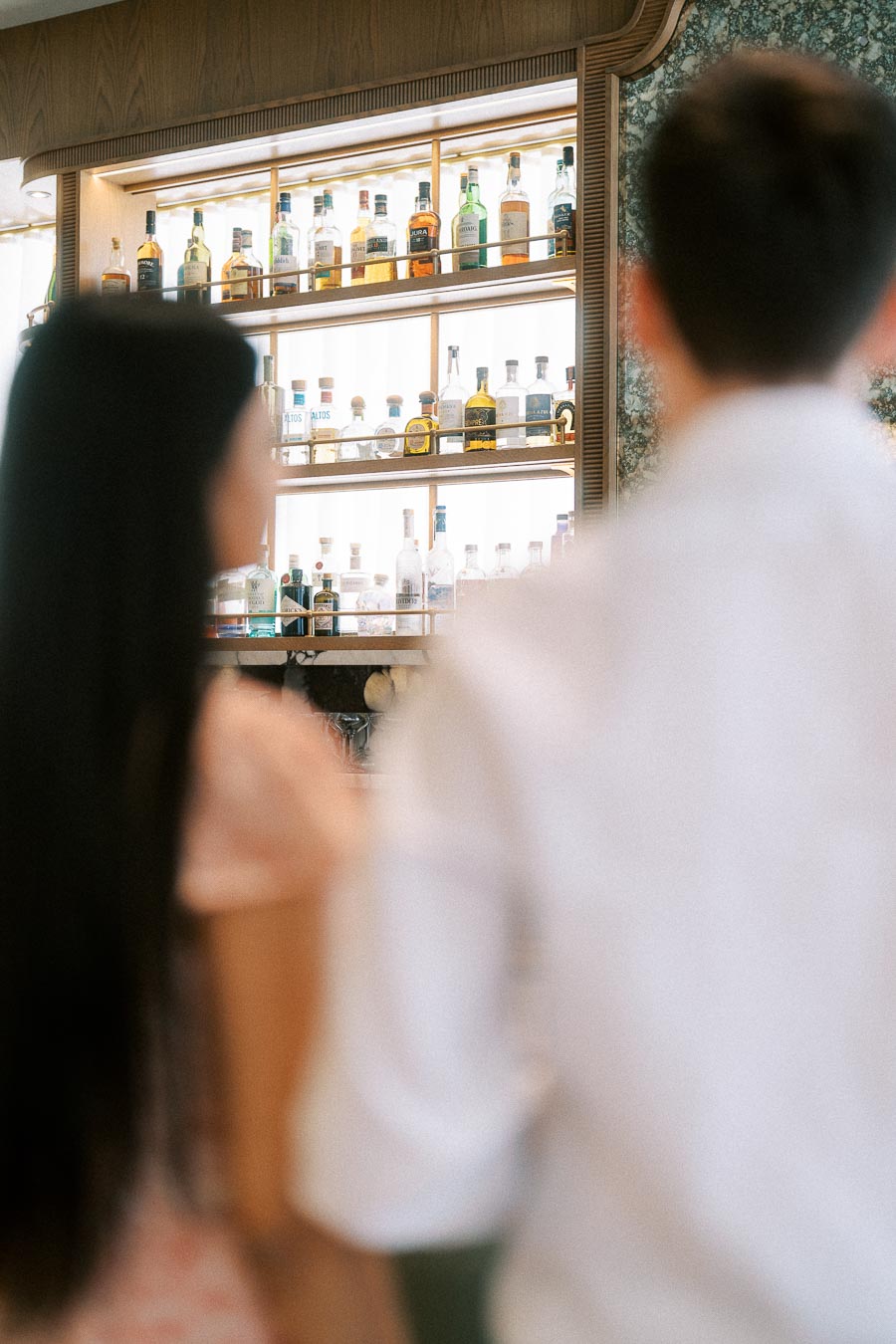 Blurred couple standing before illuminated liquor shelves in a Toronto bar interior