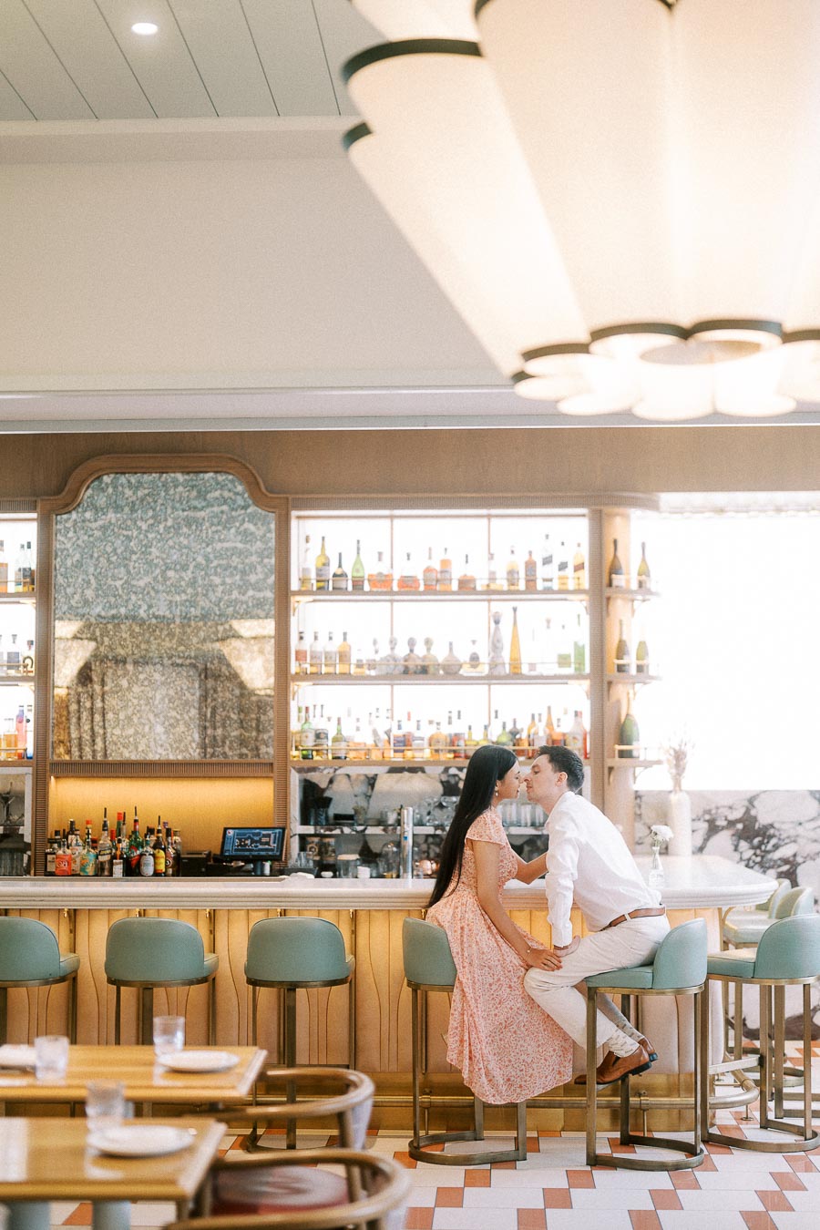 Couple kissing on bar stools inside a bright Toronto restaurant bar
