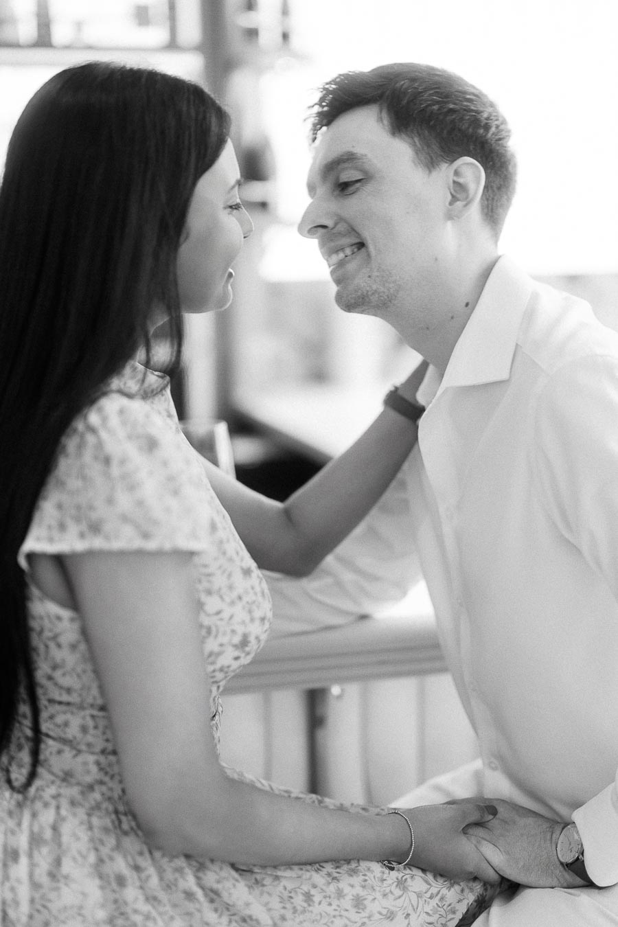Black and white close-up of an engaged couple smiling face to face indoors