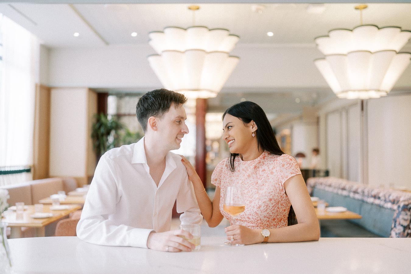 Couple smiling at a bright restaurant bar during their Toronto engagement session