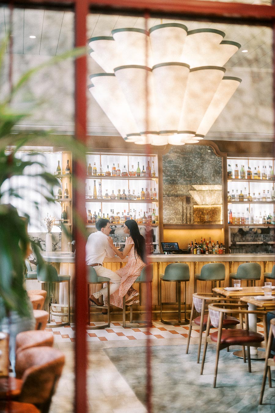 Couple sitting at a stylish Toronto bar beneath a large chandelier
