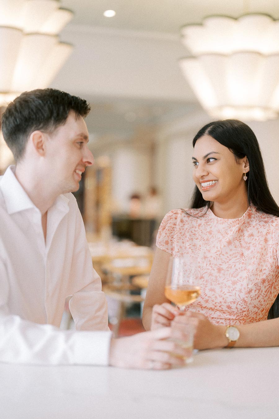 Couple smiling at each other over wine in a softly lit restaurant