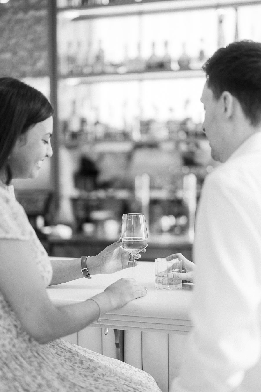Couple sharing drinks at a bright Toronto bar during their engagement session