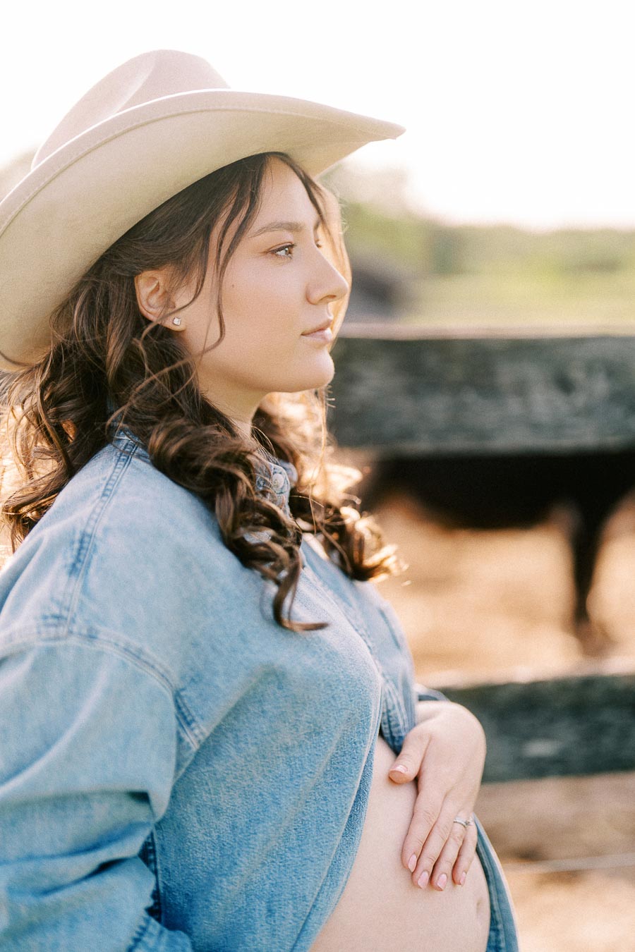 Expectant mother in cowboy hat by a paddock at The Green Acres