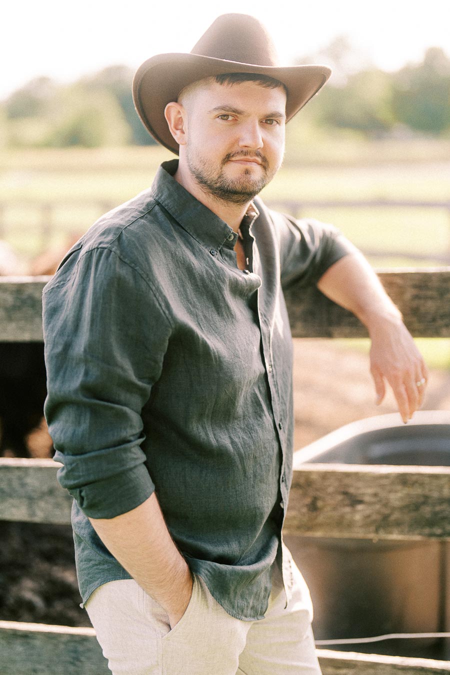 Man in cowboy hat leaning on a wooden fence at The Green Acres