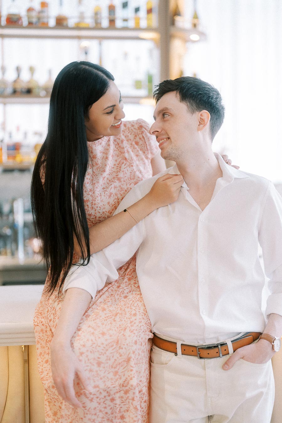Couple smiling together at a bright Toronto bar during their engagement session