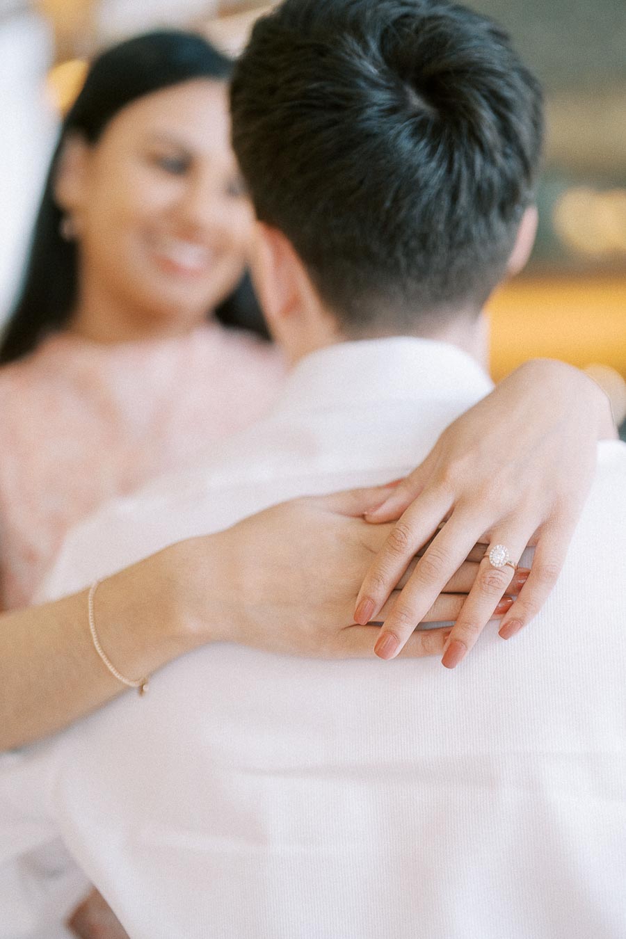 Woman’s engagement ring visible as she embraces her partner indoors