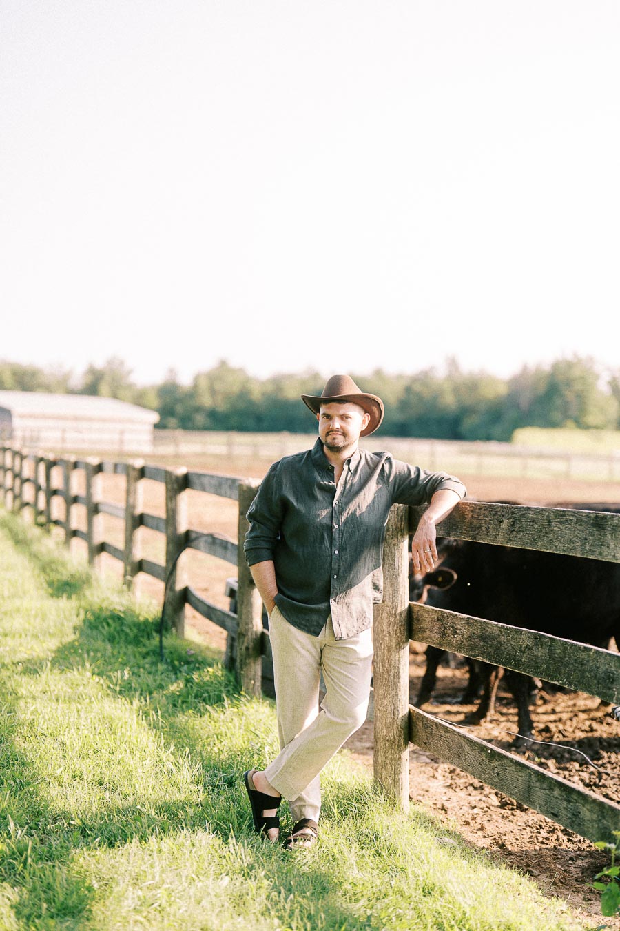 Man in cowboy hat leaning on a farm fence at The Green Acres