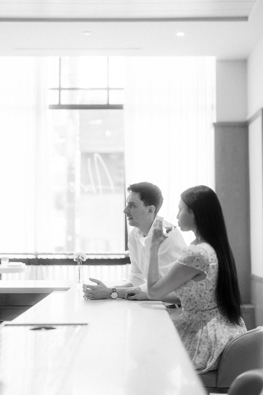 Couple seated at a bright bar counter during an indoor engagement session