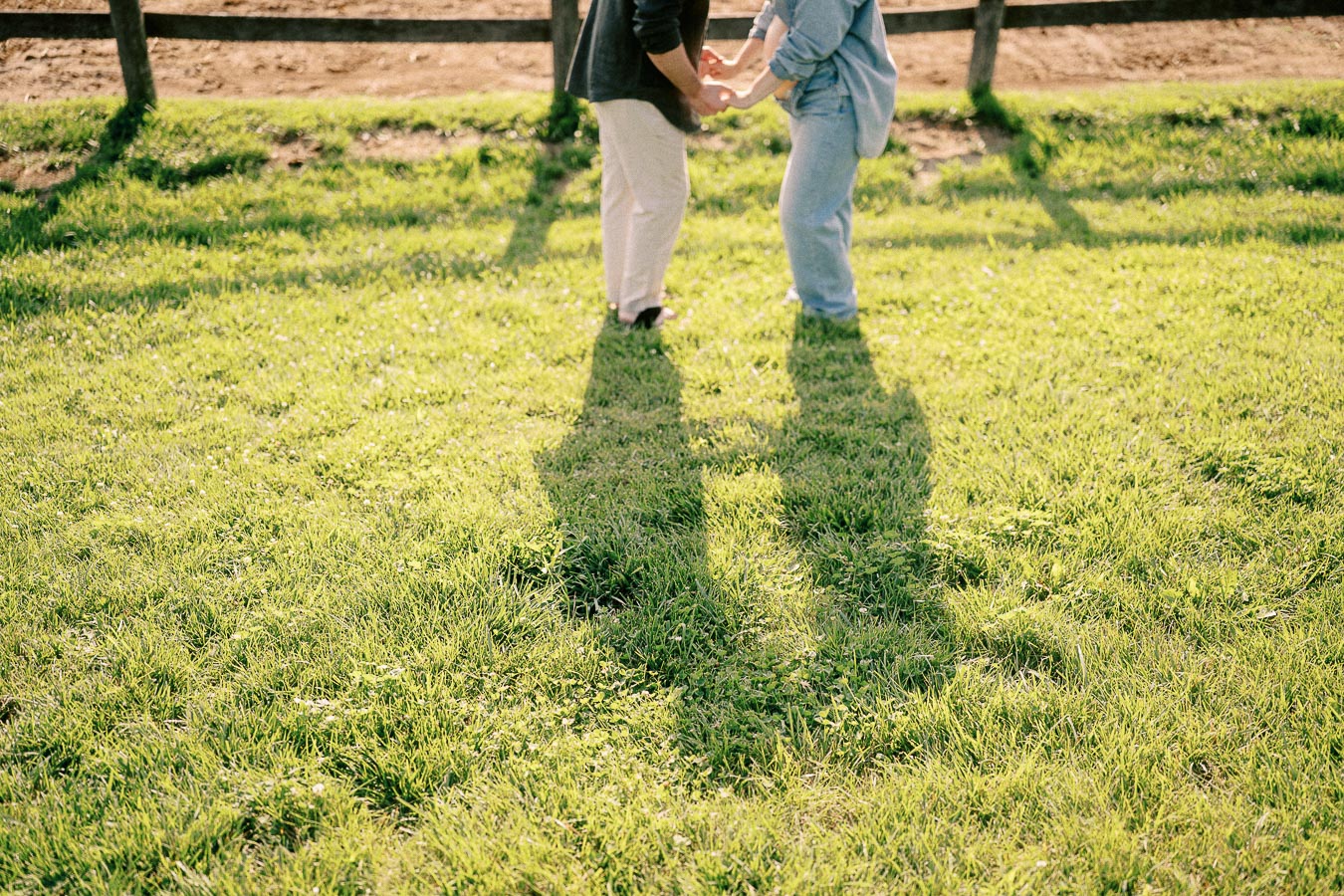 Couple holding hands on grassy farm lawn at The Green Acres