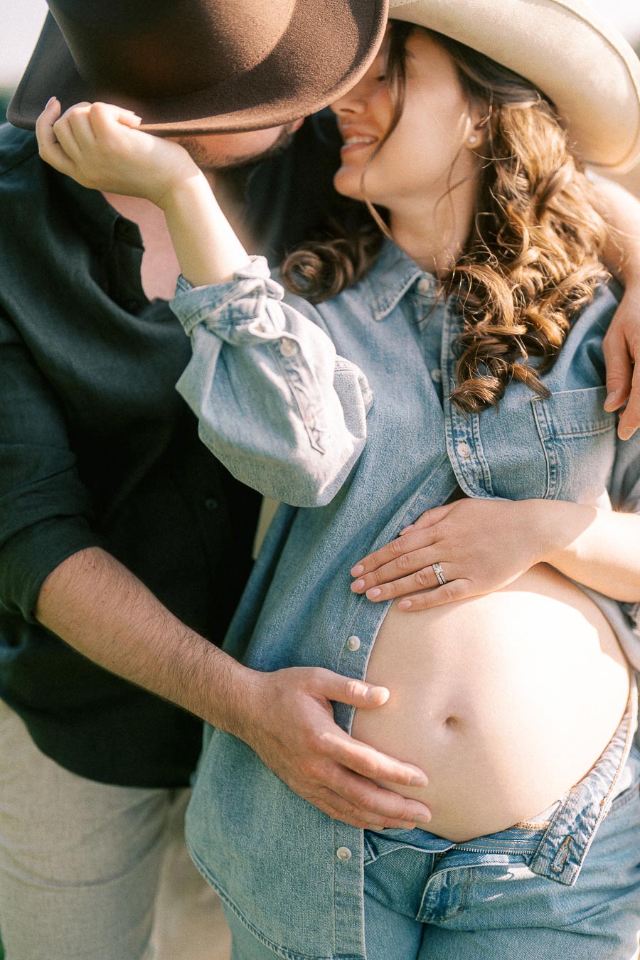 Expectant couple in cowboy hats holding a pregnant belly
