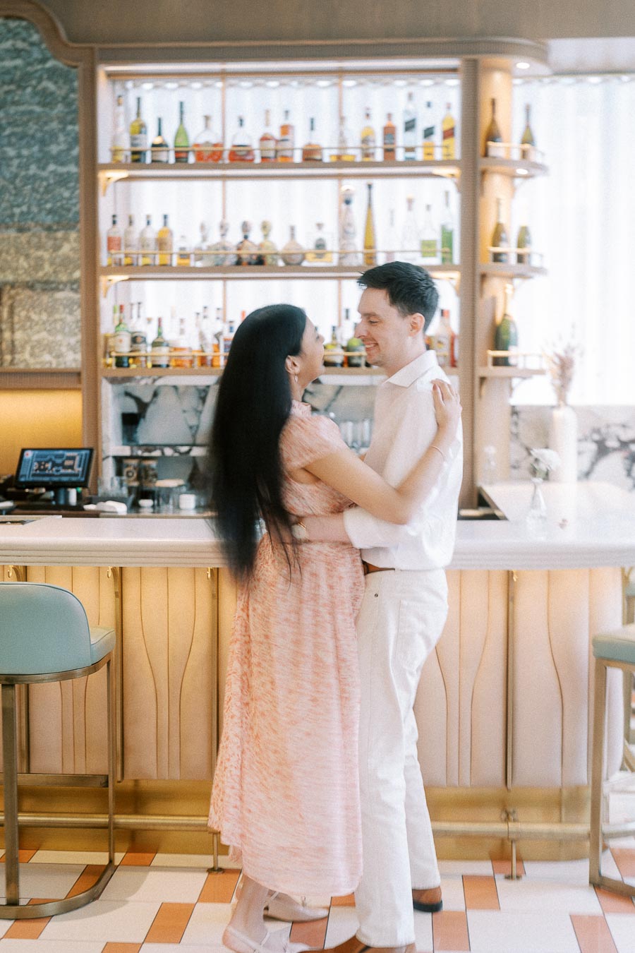 Couple embracing and smiling in front of a softly lit bar in Toronto