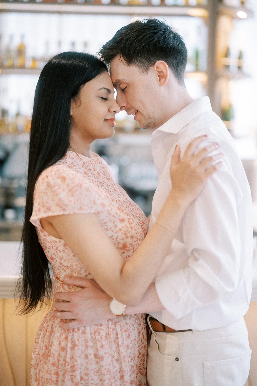 Couple embracing with foreheads touching inside a softly lit bar