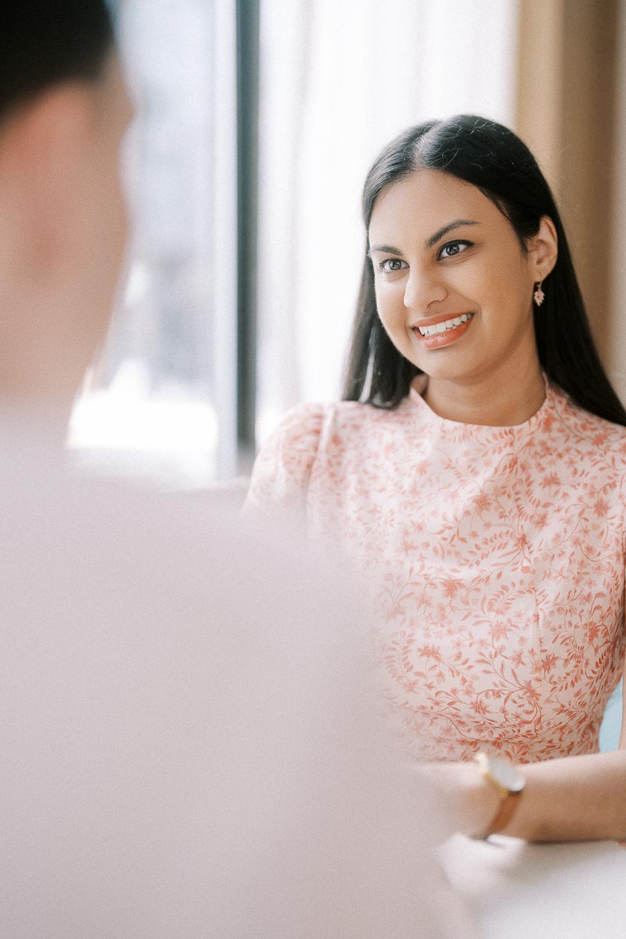 Becky smiles across a table in a softly lit Toronto engagement portrait