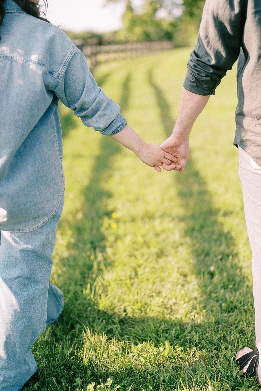 Couple holding hands while walking through grass at The Green Acres