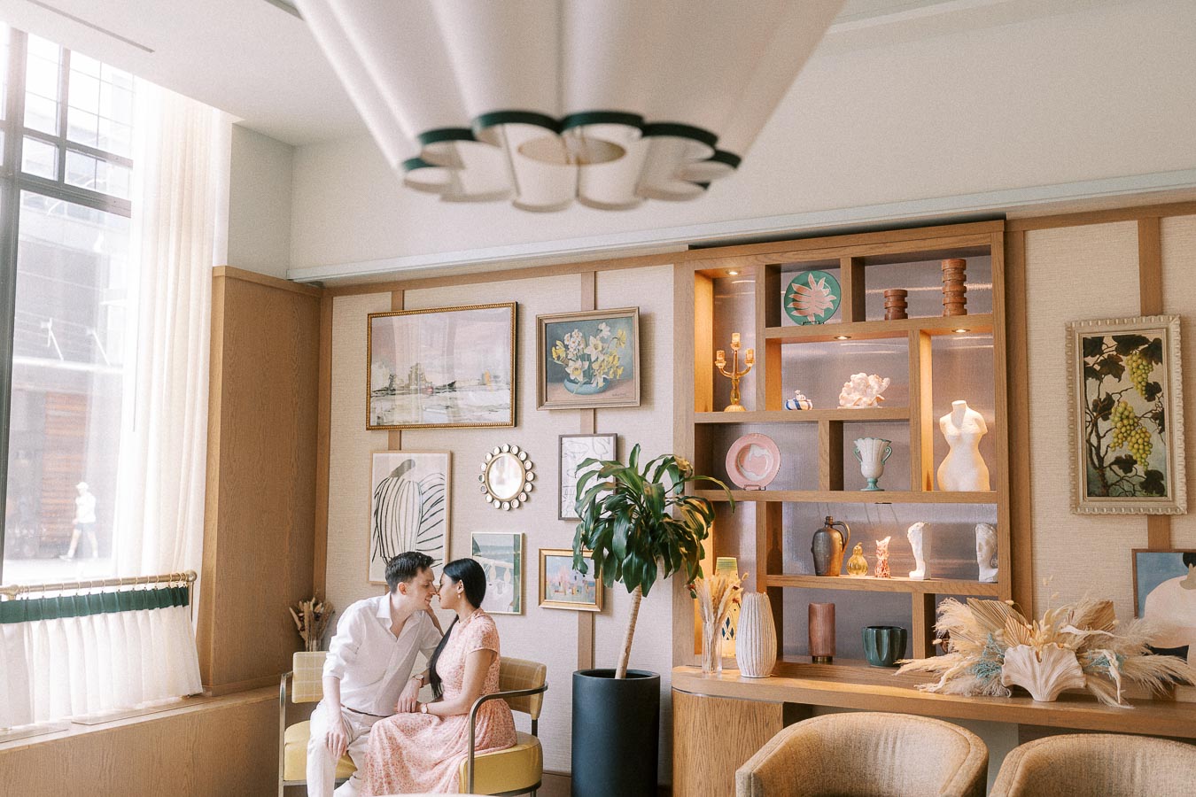 Couple sitting close in a softly lit Toronto hotel lounge with art and shelving