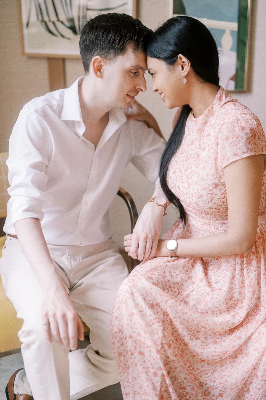 Mike and Becky sitting close together indoors, foreheads touching and smiling softly