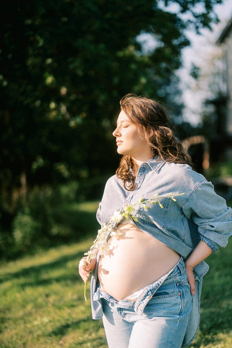 Pregnant woman in denim holding flowers at The Green Acres in Flamborough, Ontario