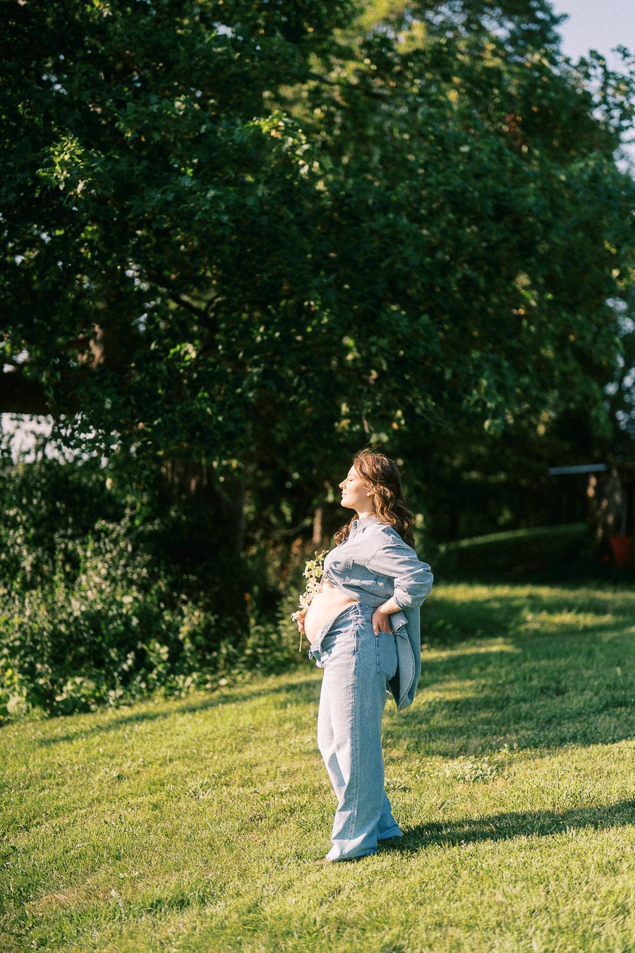Pregnant woman in denim standing on grass at The Green Acres