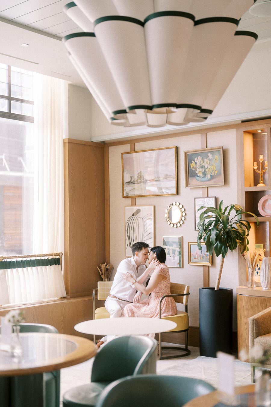 Couple cuddling on a lounge chair beneath a sculptural ceiling light in Toronto