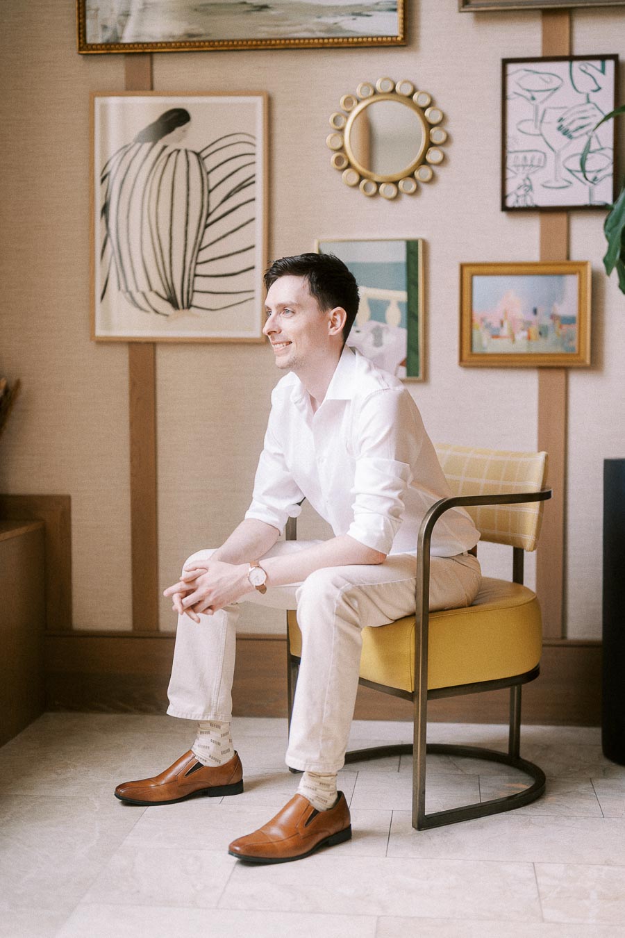 Groom-to-be seated in a yellow chair beneath framed artwork in a Toronto hotel interior