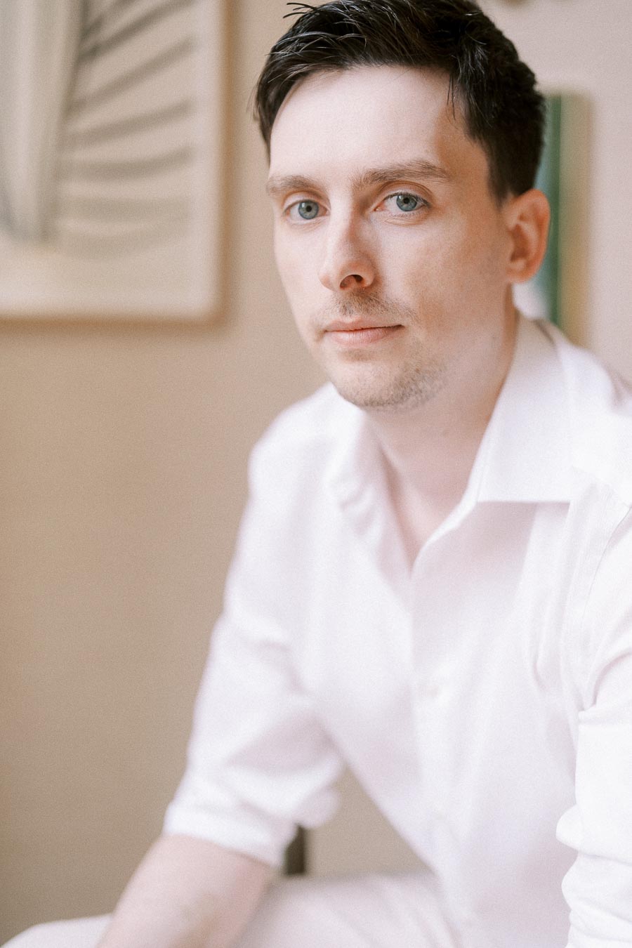 Mike in a white shirt looking toward the camera indoors