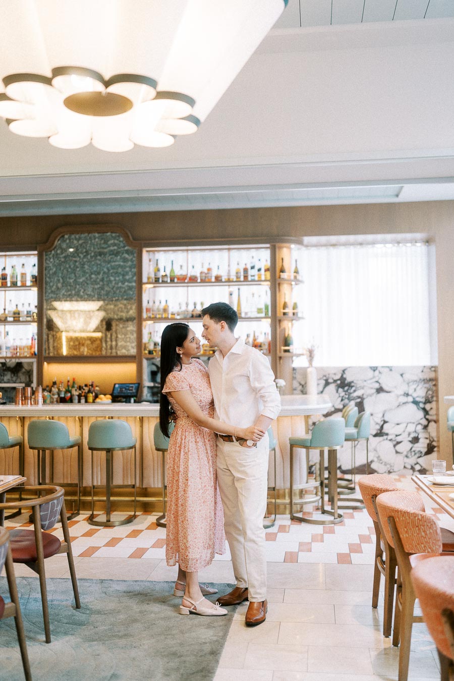Engaged couple embracing inside a pastel Toronto hotel bar