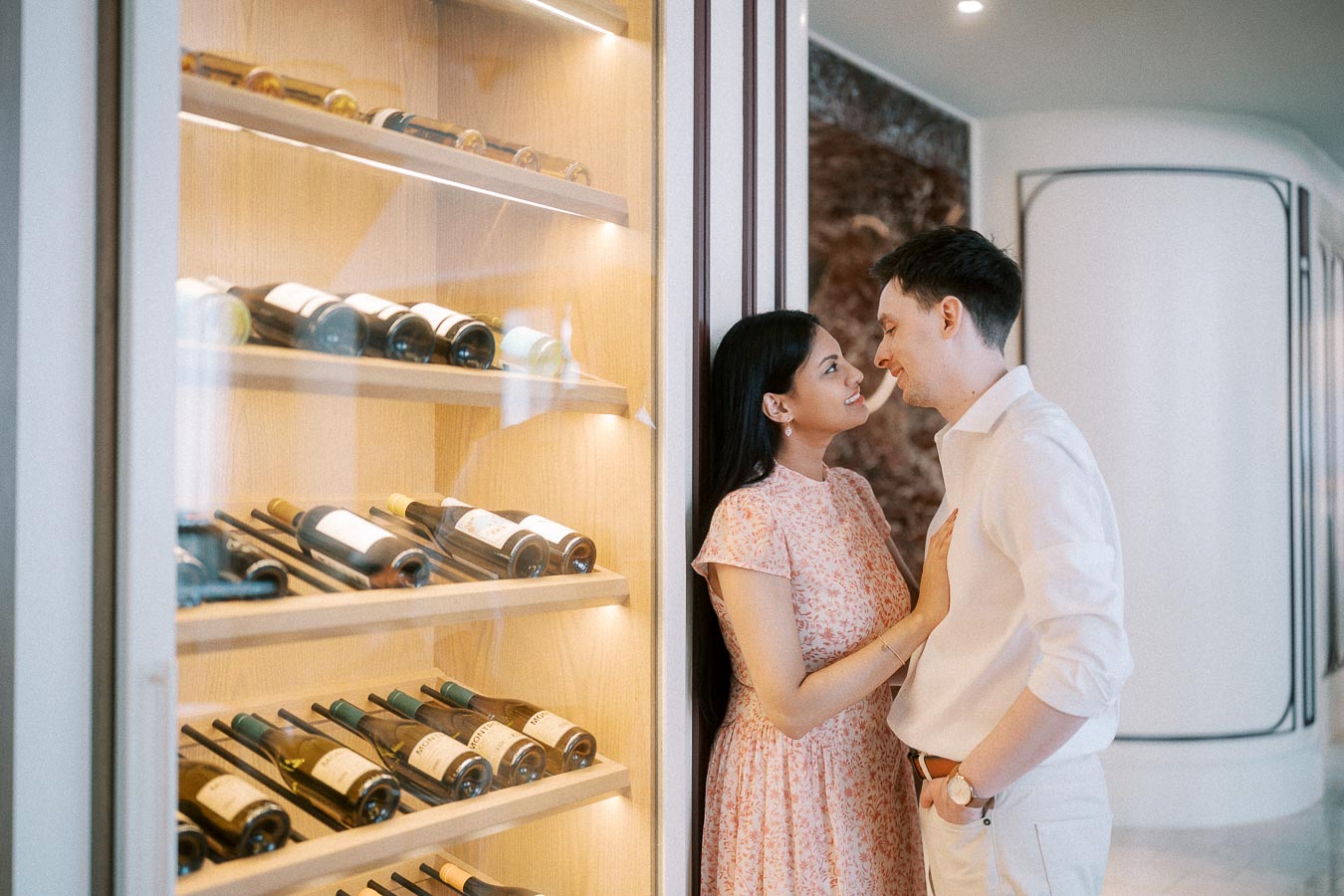 Couple smiling beside a glass wine display inside a Toronto hotel restaurant