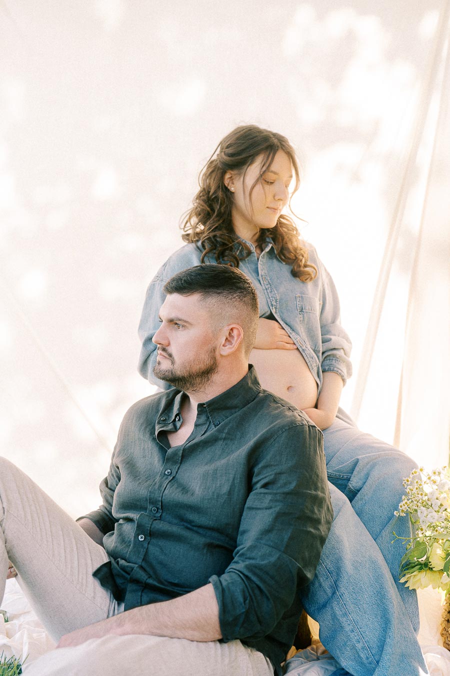 Expectant couple seated together during a soft maternity portrait at The Green Acres