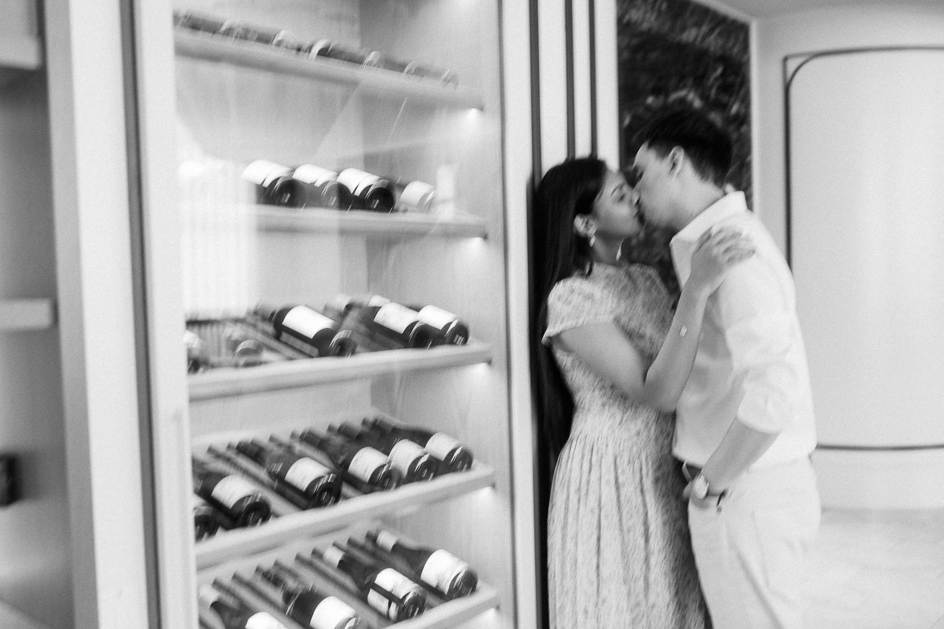 Couple kissing beside a glass wine display in a modern Toronto interior