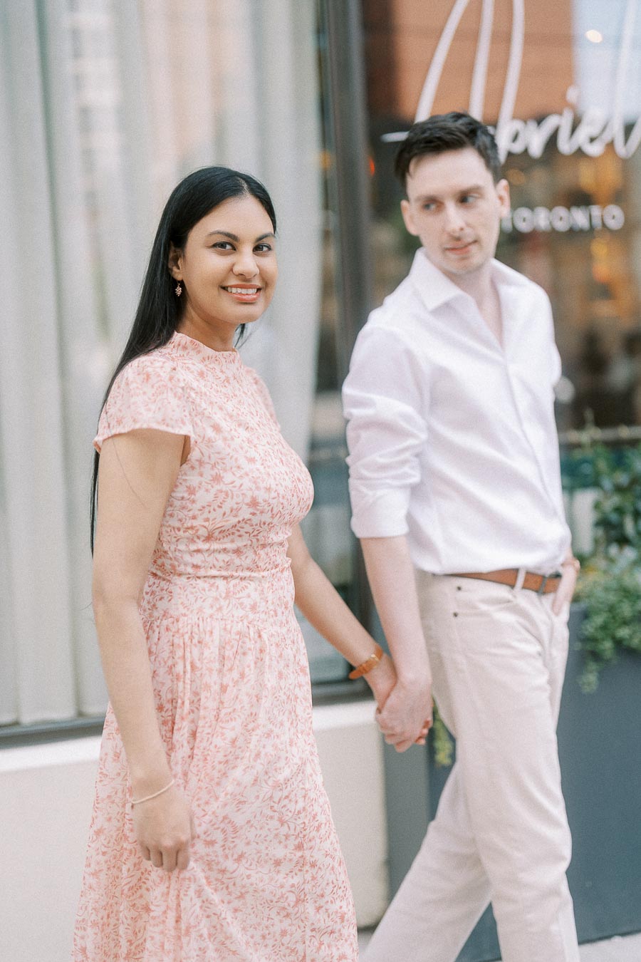 Engaged couple holding hands outside Abrielle in downtown Toronto