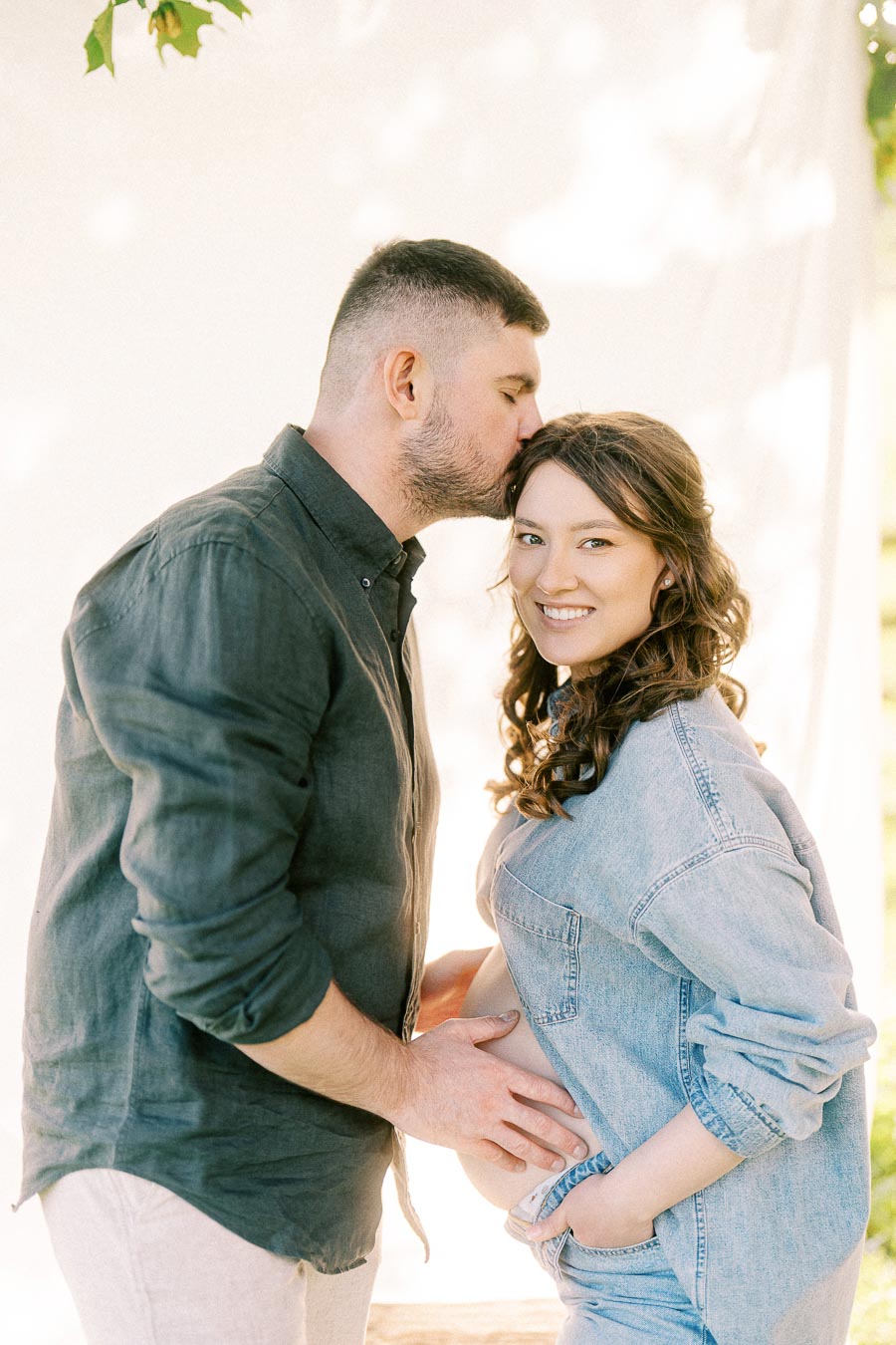 Expectant couple sharing a forehead kiss during a maternity portrait