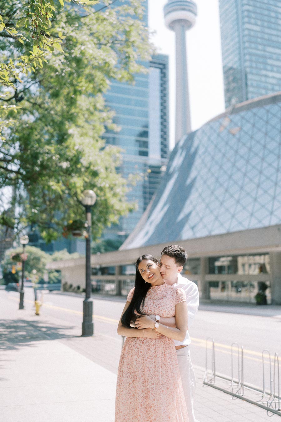 Couple embracing on a downtown Toronto sidewalk with the CN Tower behind them