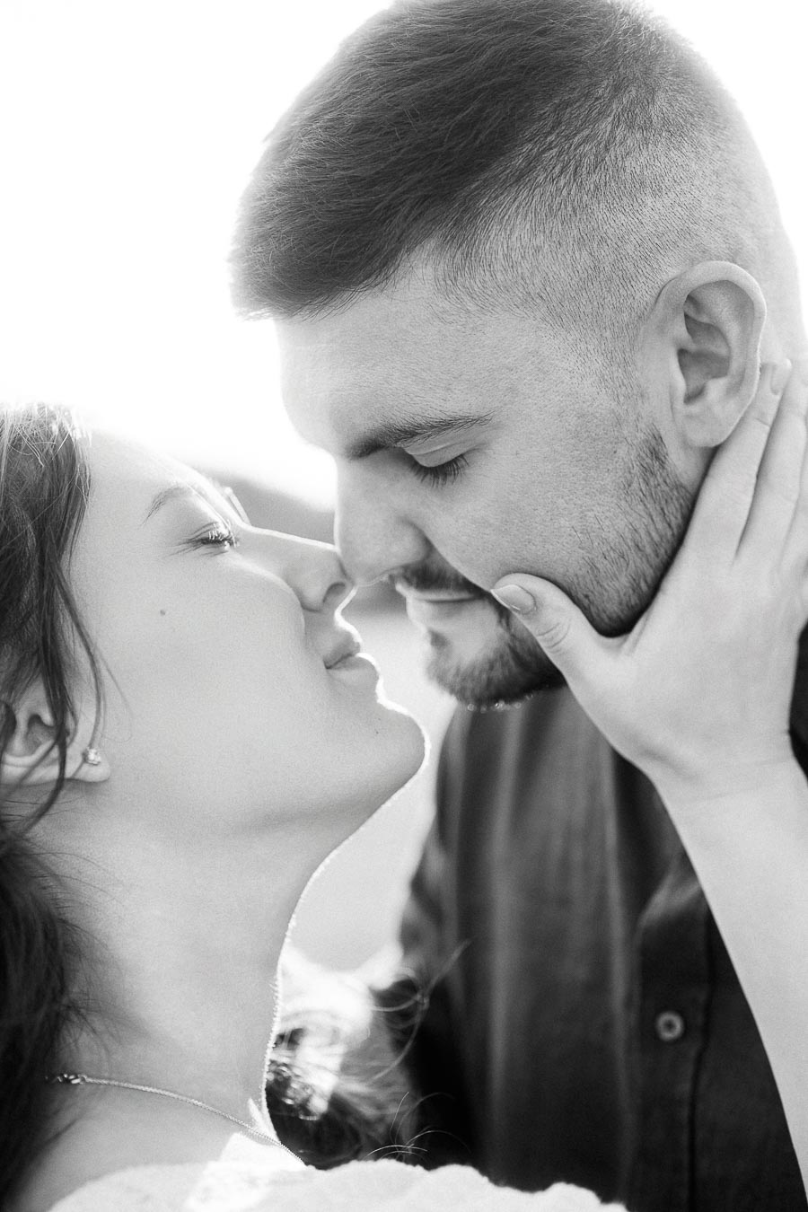 Black-and-white close-up of expectant couple touching noses