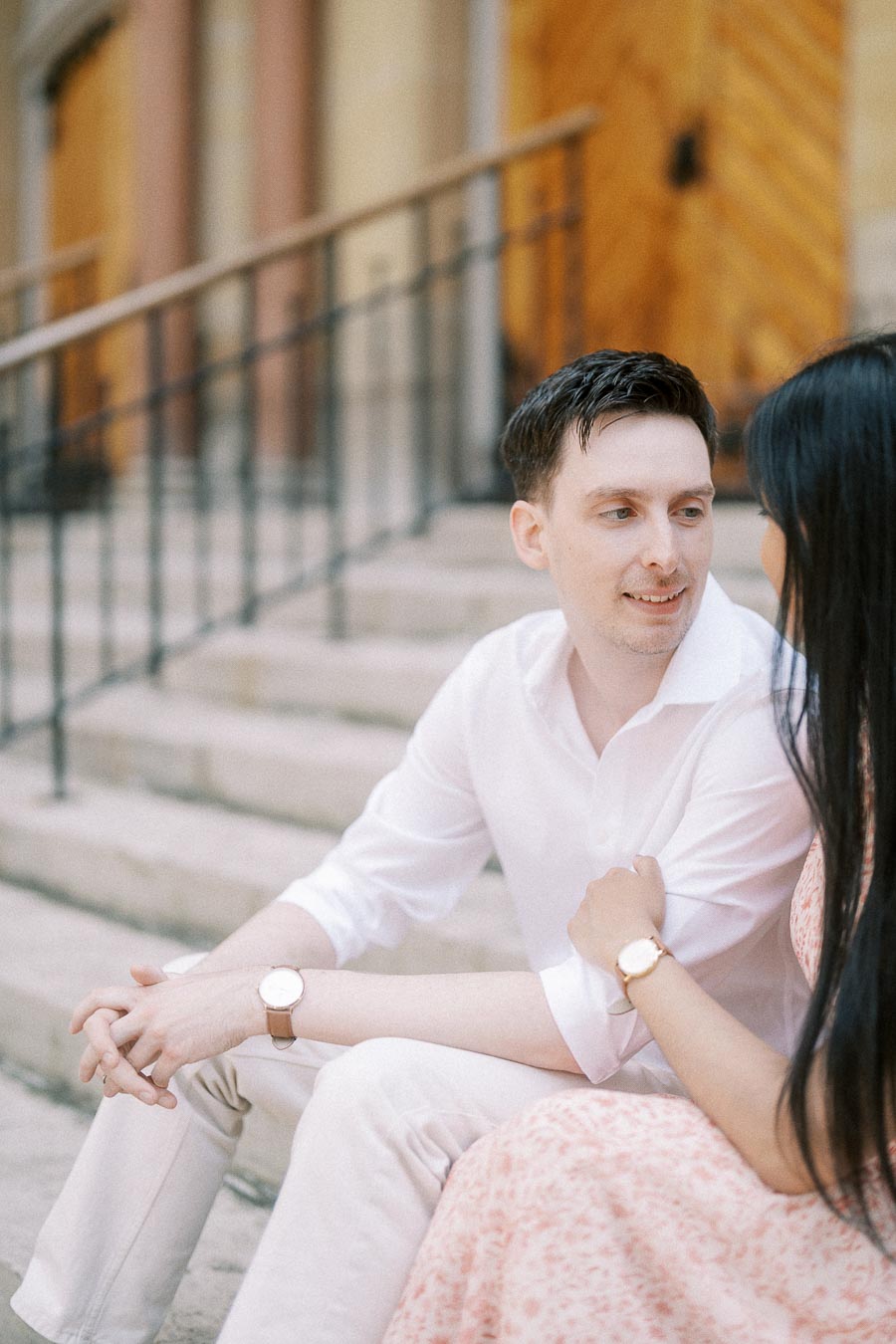 Engaged couple sitting closely on stone steps outside a building in Toronto
