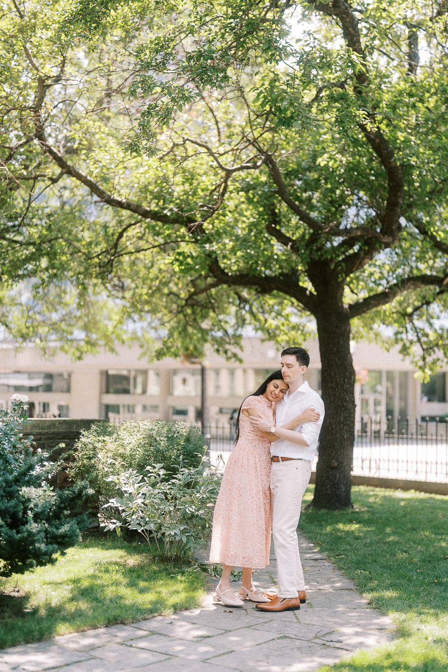 Couple embracing on a garden path beneath a leafy tree in Toronto
