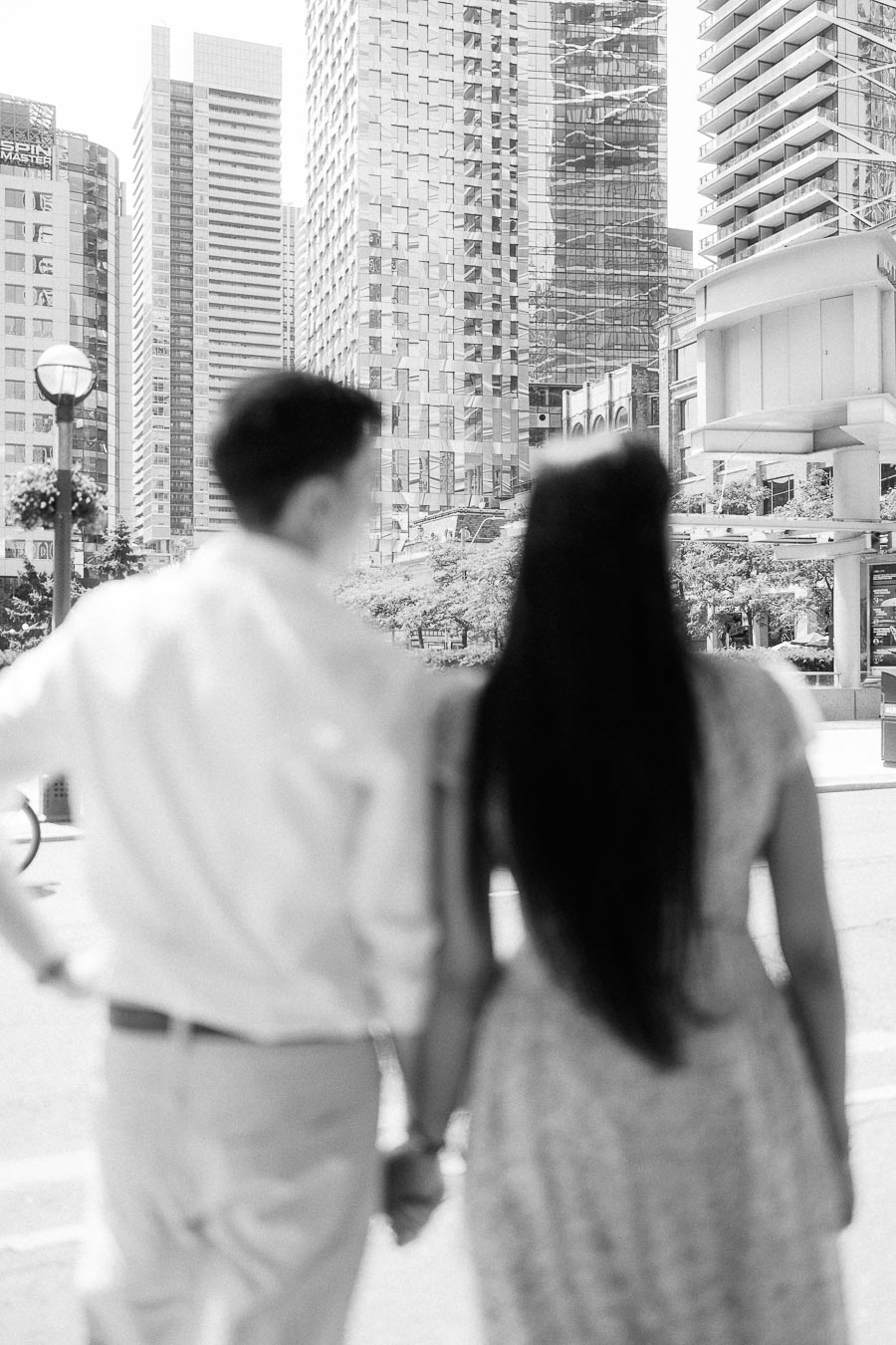 Couple holding hands while looking toward tall downtown Toronto buildings