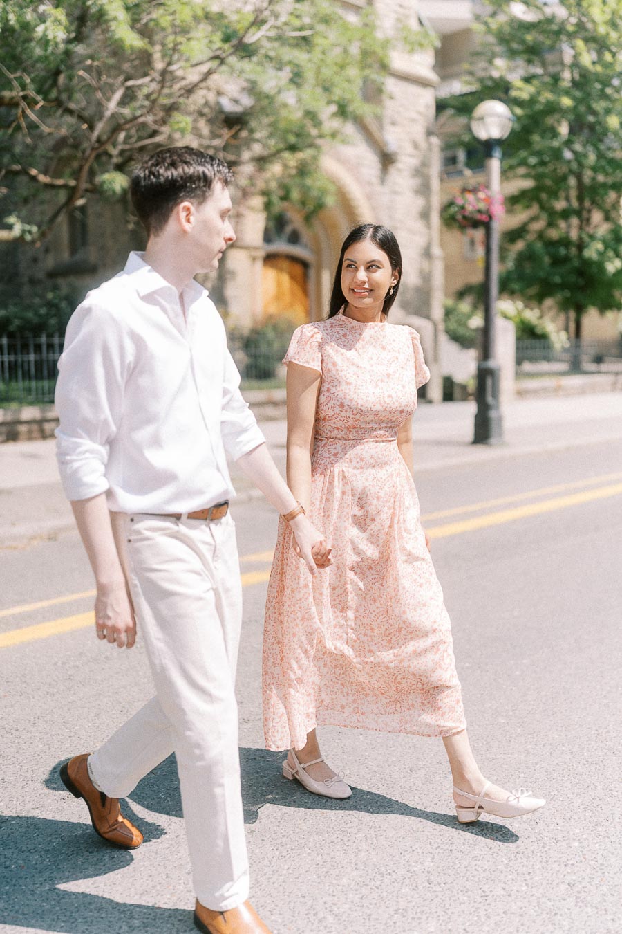 Couple holding hands while walking on a sunny Toronto street
