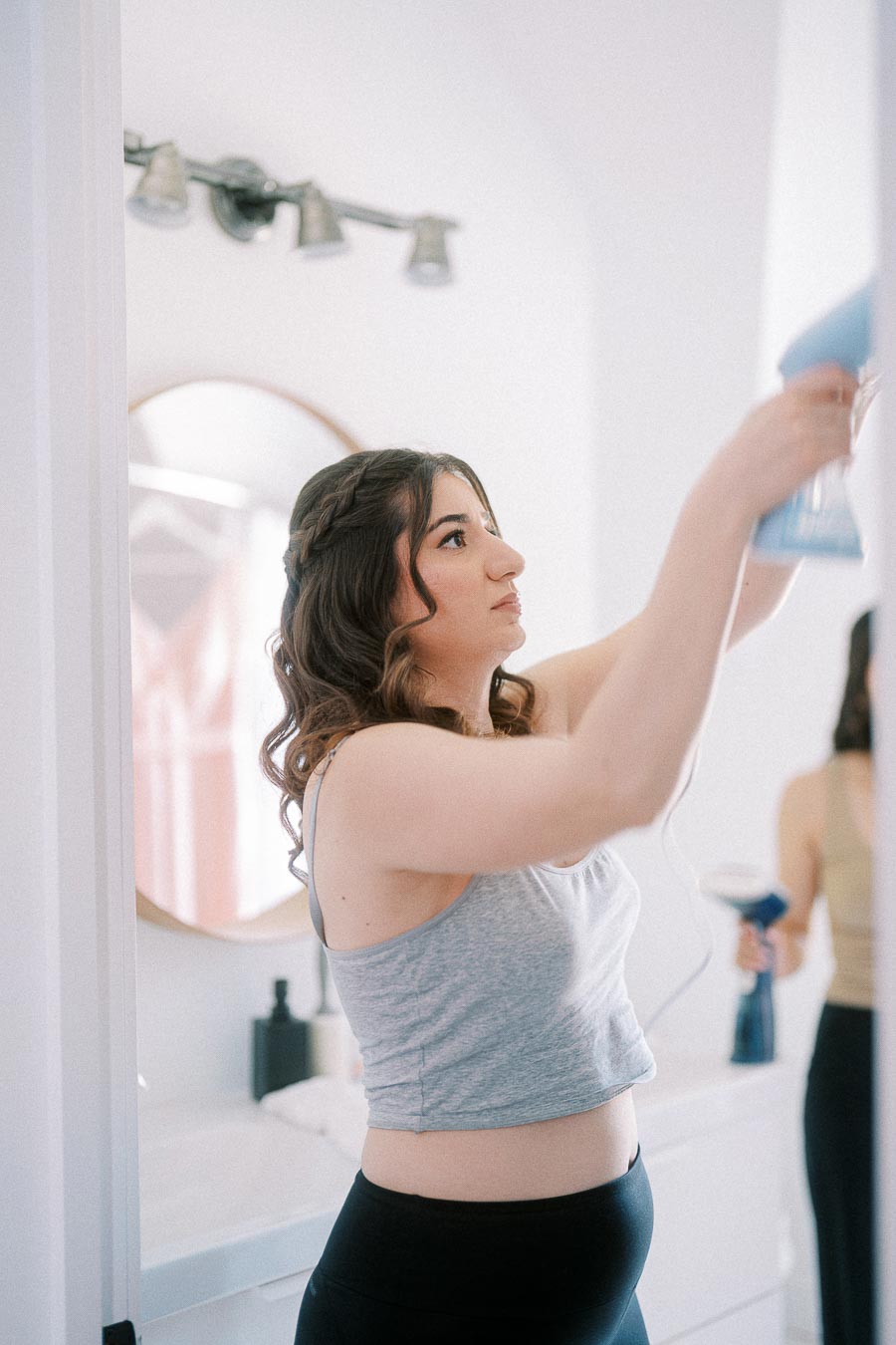 Woman with curled hair steams a garment in a bright room while getting ready for Miffy and Rawle's wedding.