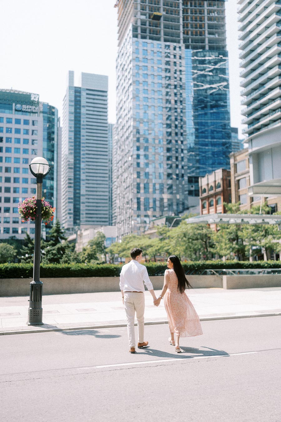 Couple holding hands while walking across a downtown Toronto street