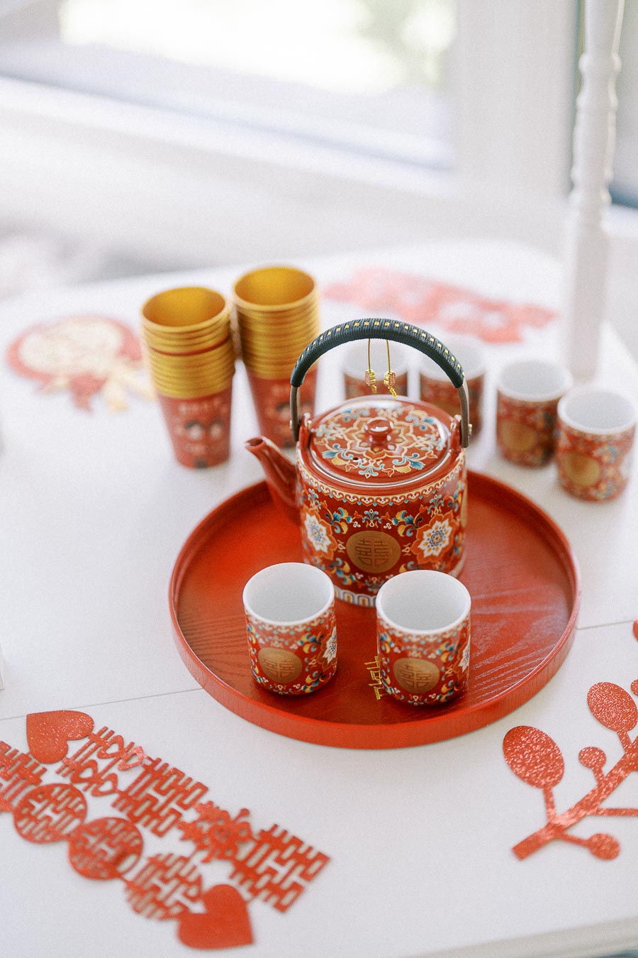 Red and gold Chinese tea ceremony teapot and cups arranged on a tray with double happiness decorations.