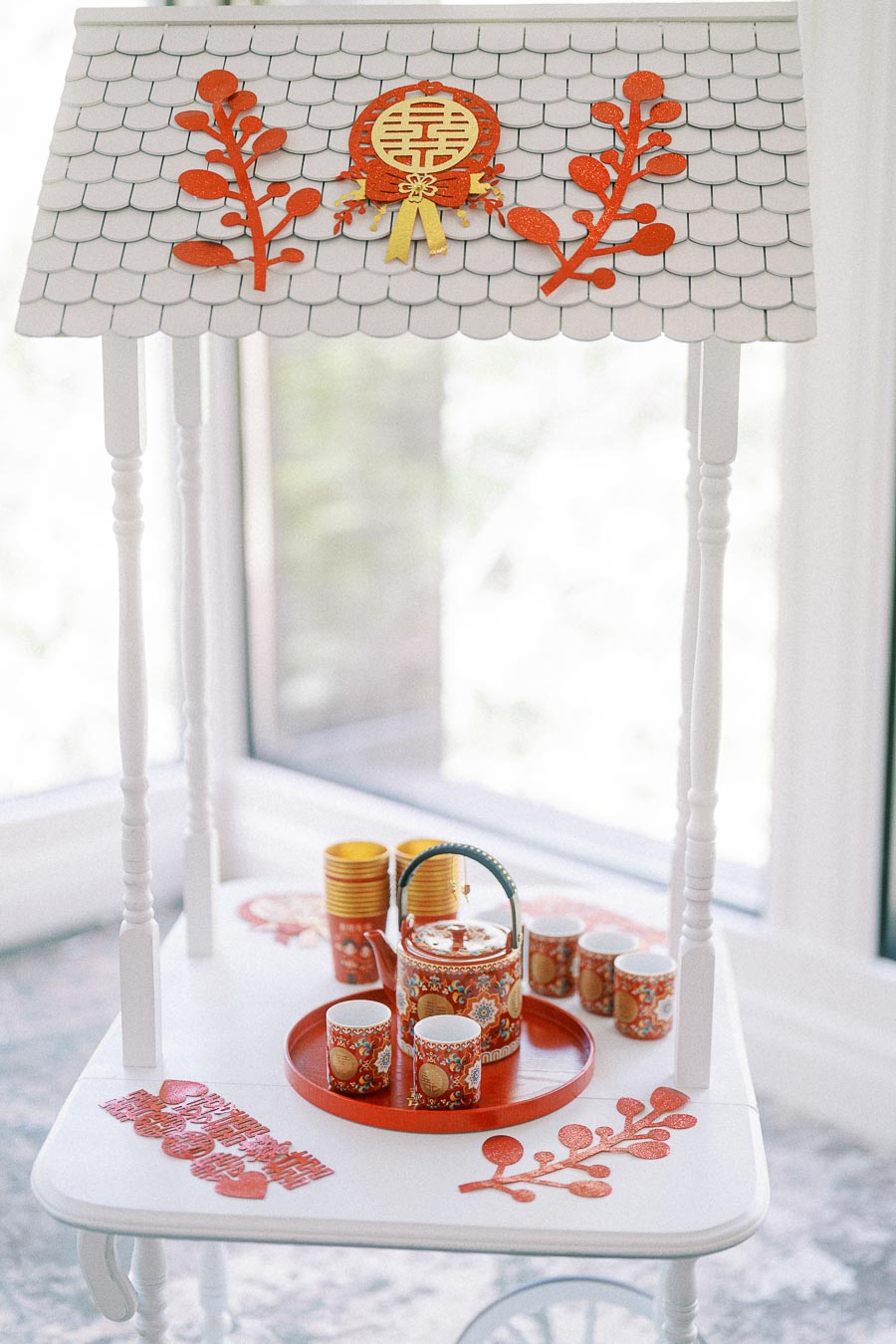Chinese tea ceremony set with red teapot, cups, and double happiness decorations on a white stand