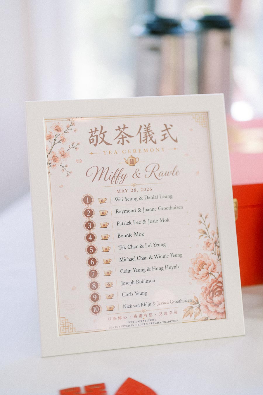 Framed tea ceremony order sign for Miffy and Rawle with Chinese characters, floral artwork, and a numbered guest list.