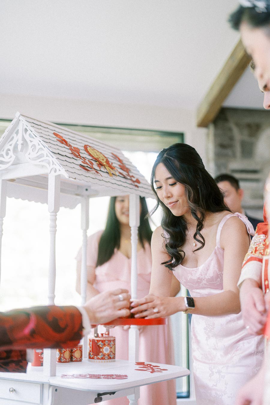 Miffy places a red tray in a white Chinese tea ceremony stand while wearing a pale pink dress.