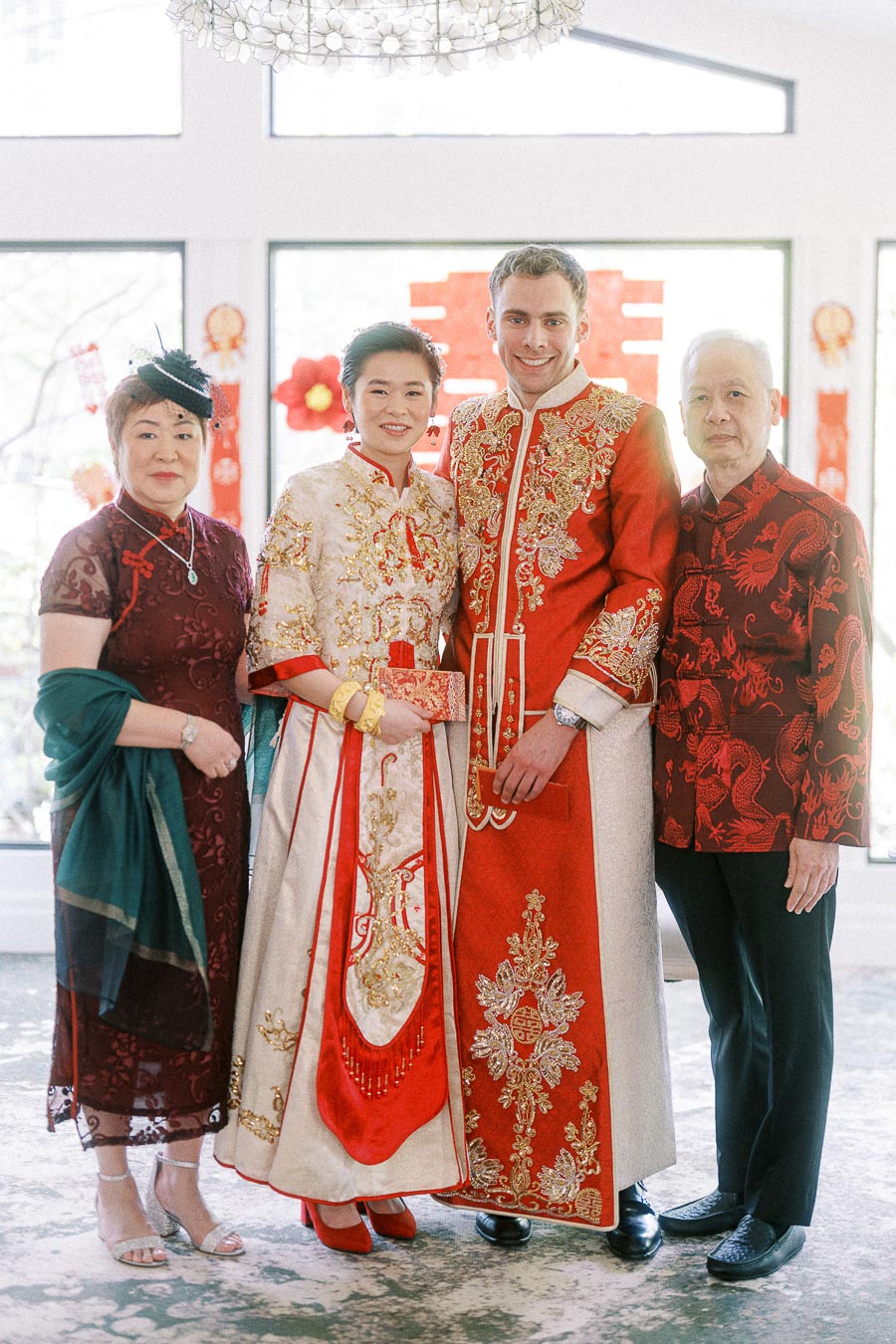 Miffy and Rawle stand with two elders in red Chinese wedding attire during their tea ceremony.