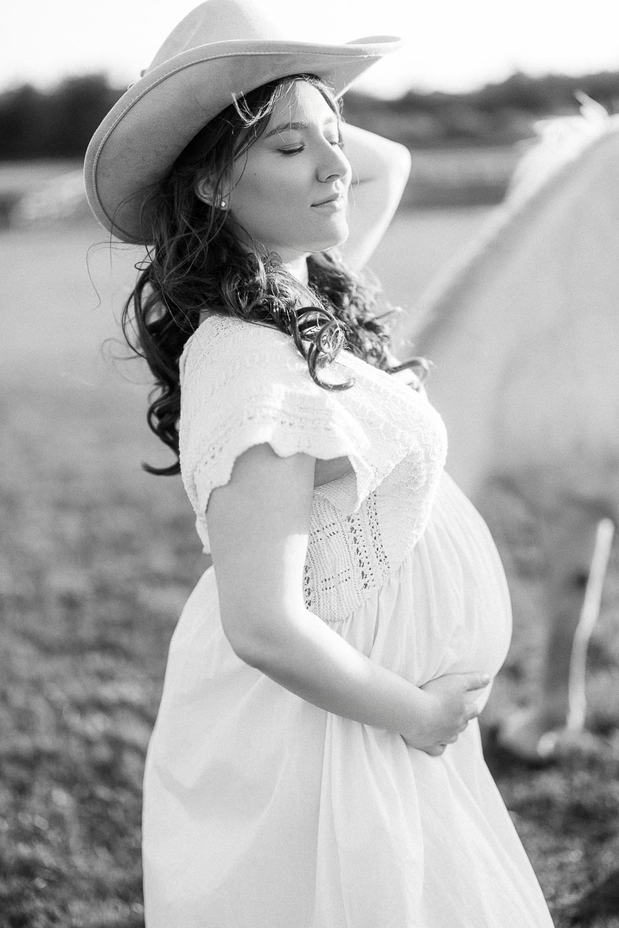 Pregnant woman in cowboy hat standing beside a horse at The Green Acres