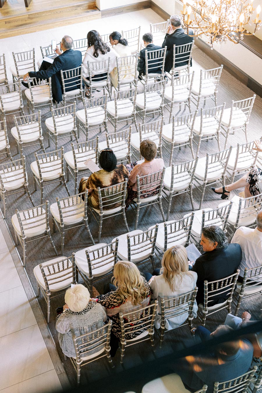 Guests seated among rows of silver chairs before an indoor wedding ceremony at Ancaster Mill