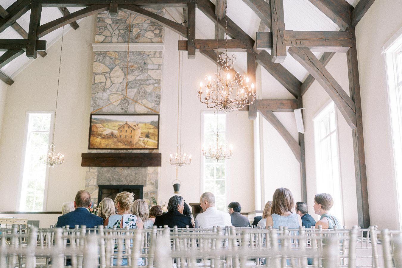 Guests seated in a bright chapel with chandeliers, timber beams, and a stone fireplace at Ancaster Mill.