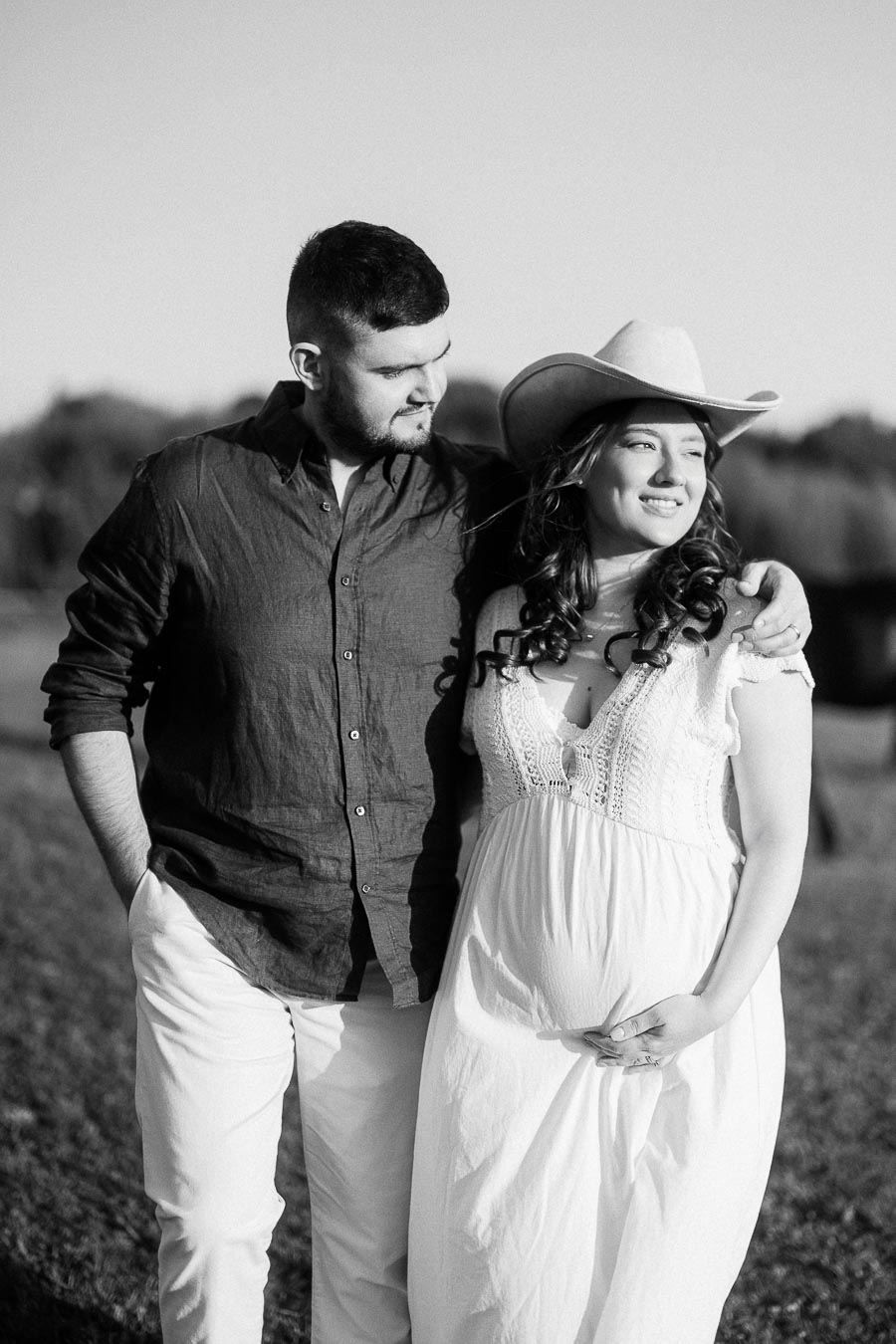 Expectant couple standing together in a field at The Green Acres