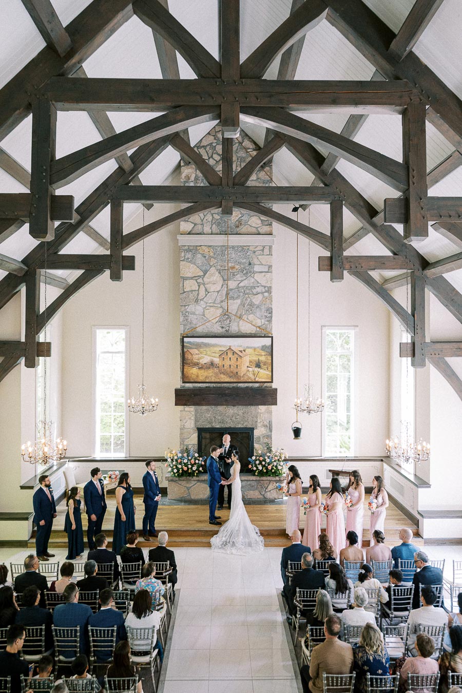 Bride and groom stand at the altar during a chapel wedding ceremony beneath dark wooden beams.